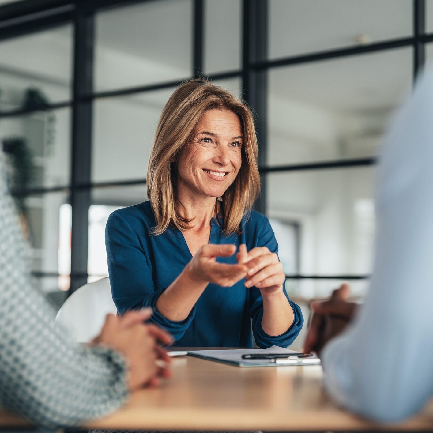 A candidate confidently presents their resume during a job interview with a panel of professionals.  Company owner on a meeting with employee. Middle aged businesswoman in a conversation with a colleague. Lawyer consulting client during formal meeting. Job interview and hiring process.
